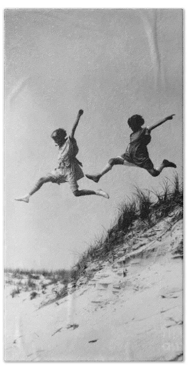 1920s Bath Towel featuring the photograph Two Girls Leaping Off Sand Dune by H Armstrong Roberts and ClassicStock