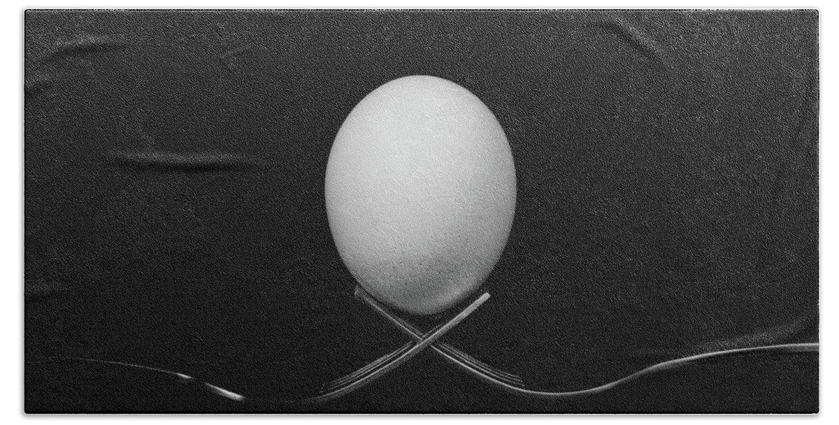 Egg Bath Towel featuring the photograph White egg resting on two metal and shiny forks on a black backg by Michalakis Ppalis