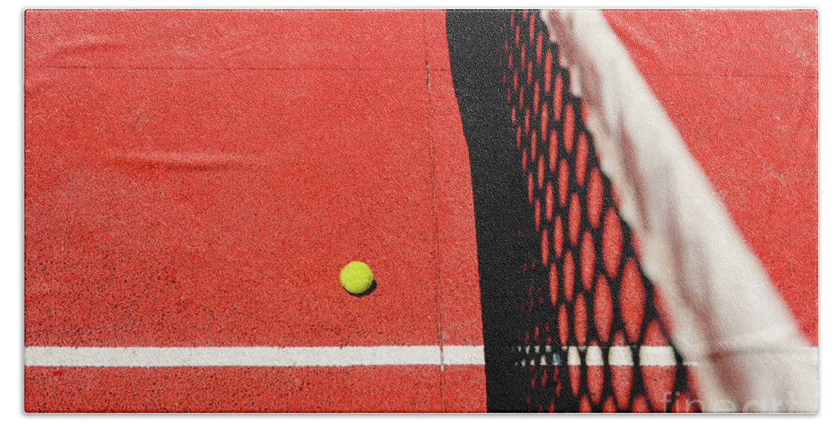 Ace Bath Towel featuring the photograph A tennis ball on the textured floor of a red court near the net after losing a match point. by Joaquin Corbalan