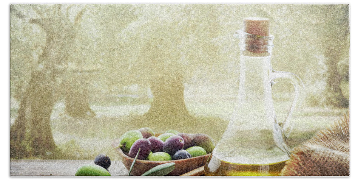 Olive Hand Towel featuring the photograph Olives and bottle of olive oil on wooden table in olive garden by Jelena Jovanovic