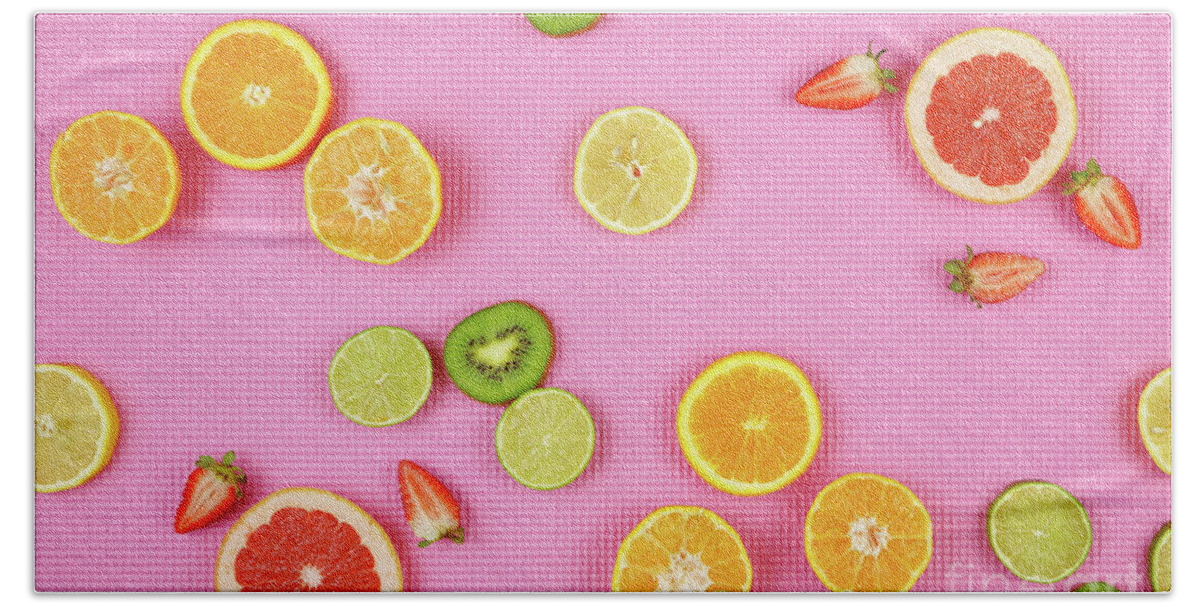 Summer Hand Towel featuring the photograph Summer theme background with fruit, citrus and flowers on pink backdrop. by Milleflore Images