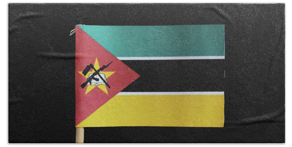 Mozambique Hand Towel featuring the photograph A national flag of Mozambique on toothpick on black background. Consists of horizontal tricolour of green, white edged black and yellow with the red isosceles triangle by Vaclav Sonnek