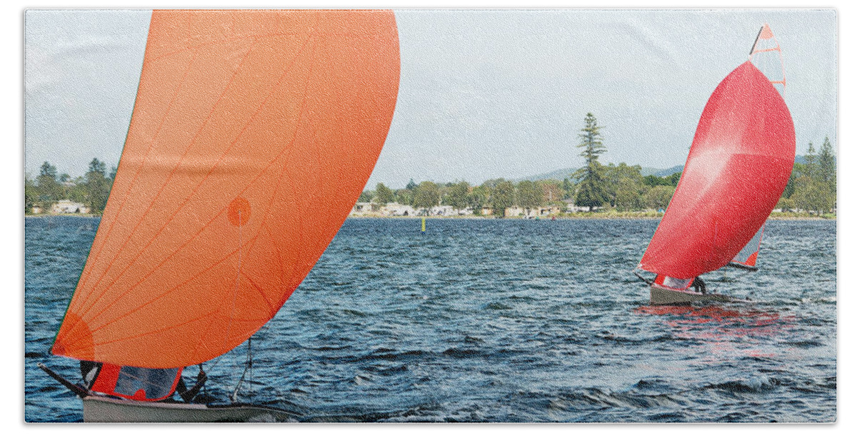 Landscape Hand Towel featuring the photograph Children Sailing small sailboat with colourful orange and red sa by Geoff Childs