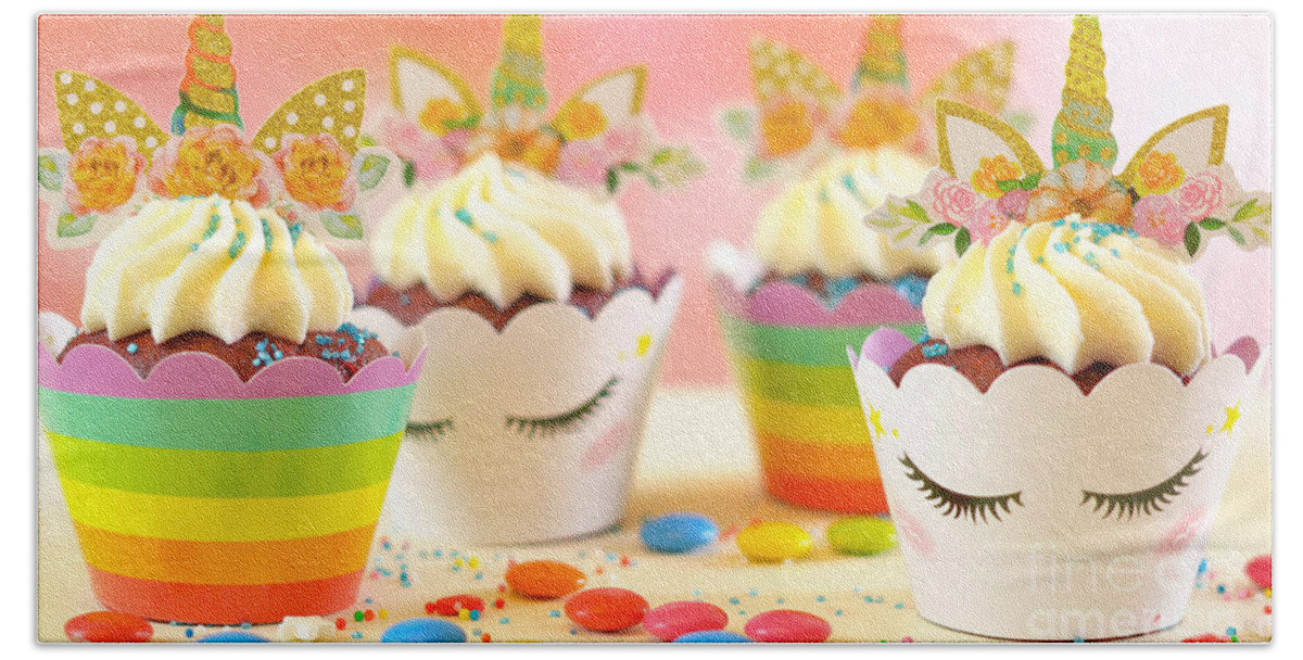 Cupcake Bath Towel featuring the photograph Decorating children's birthday party unicorn themed cupcakes, closeup. by Milleflore Images