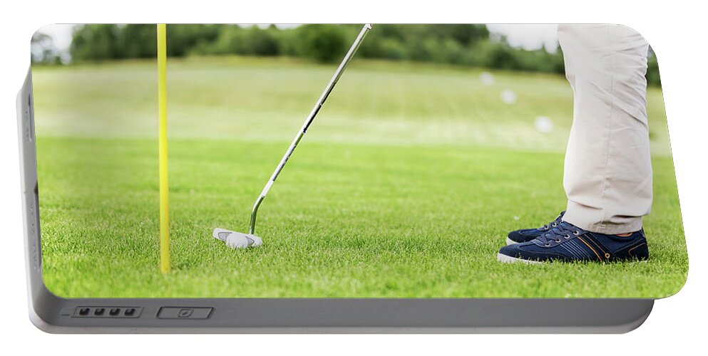 Golf Portable Battery Charger featuring the photograph Golfer putting ball in the hole on a golf course. #1 by Michal Bednarek