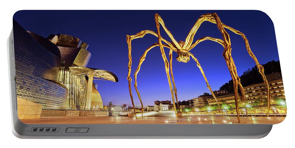 Guggenheim Portable Battery Charger featuring the photograph Guggenheim museum and spider at night in Bilbao by Mikel Martinez de Osaba