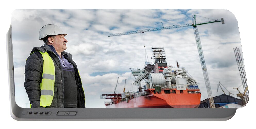 Engineer Portable Battery Charger featuring the photograph Shipbuilding engineer at the dockside in a port. by Michal Bednarek