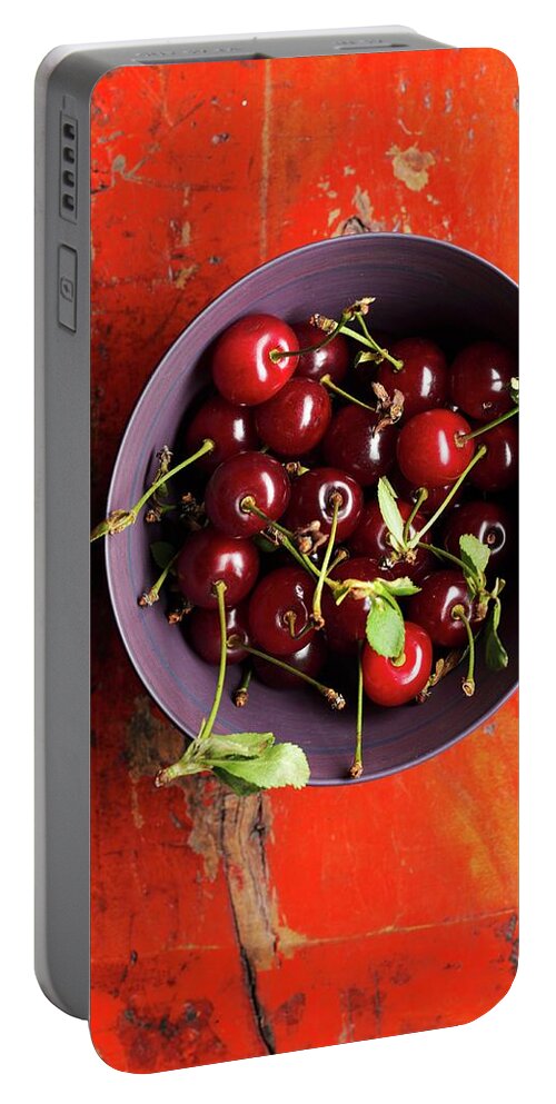 Ip_11298747 Portable Battery Charger featuring the photograph A Bowl Of Sour Cherries With Leaves by Ruth Kng