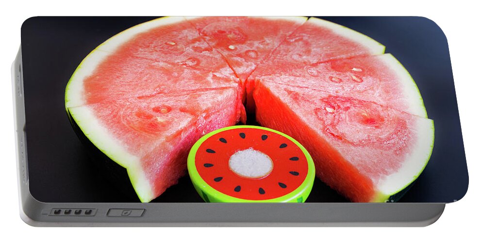 Backdrop Portable Battery Charger featuring the photograph A large slice of watermelon divided into smaller pieces next to by Joaquin Corbalan