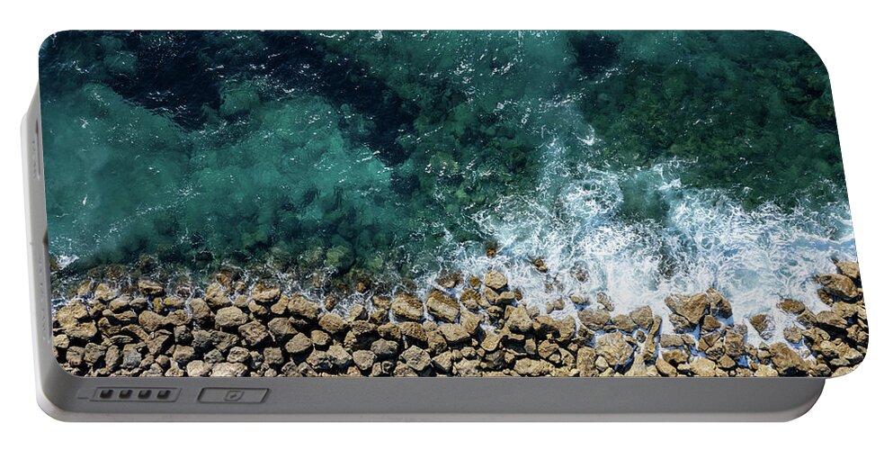 Seascape Portable Battery Charger featuring the photograph Aerial view from flying drone of crystal blue ocean water and sea wall. by Michalakis Ppalis