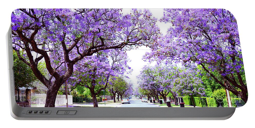 Jacaranda Portable Battery Charger featuring the photograph Beautiful purple flower Jacaranda tree lined street in full bloom. by Milleflore Images