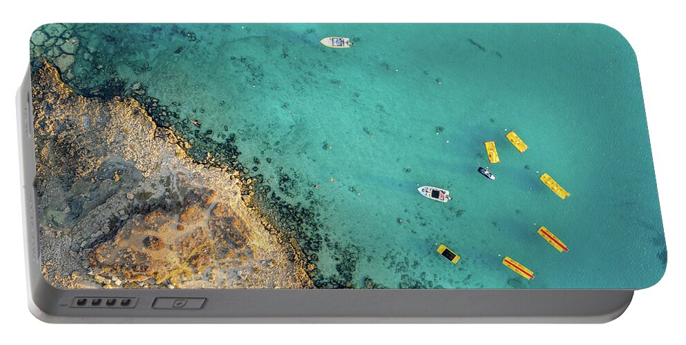Seascape Portable Battery Charger featuring the photograph Drone aerial of seascape with idyllic blue calm blue water. Fig tree bay beach Protaras Cyprus by Michalakis Ppalis