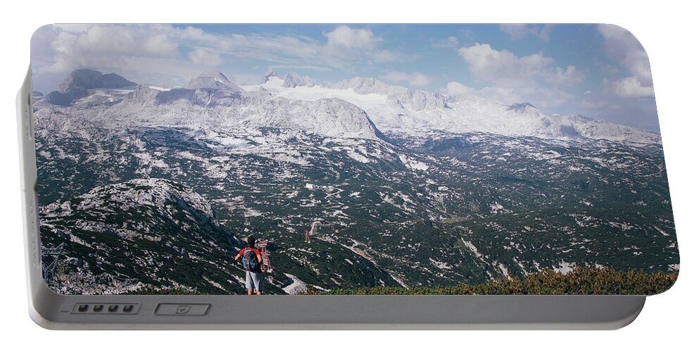Sportive Portable Battery Charger featuring the photograph Man with a backpack looks at the Dachstein massif by Vaclav Sonnek