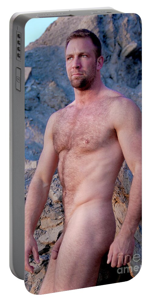 Young Portable Battery Charger featuring the photograph Rugged masculine nude man poses by cliffs my the ocean. by Gunther Allen