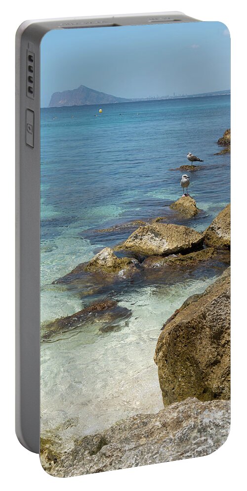 Mediterranean Portable Battery Charger featuring the photograph Turquoise blue sea water and rocks in Calpe 2 by Adriana Mueller