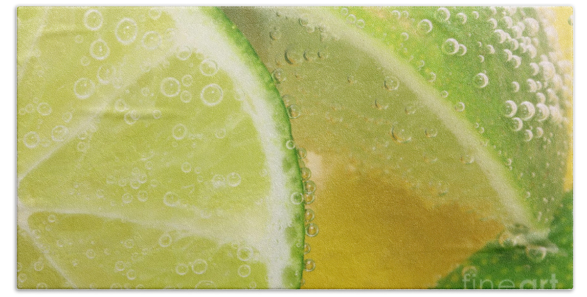 Lemon Beach Towel featuring the photograph Lemon and lime slices in water by Simon Bratt