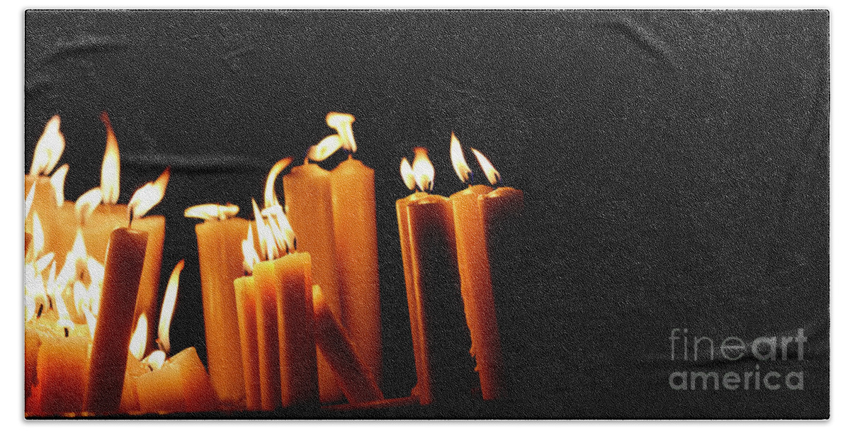 Candle Beach Towel featuring the photograph Religious candles on black background. Yellow candlelight f by Jelena Jovanovic