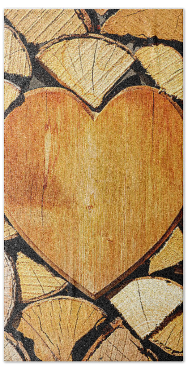 Pile Beach Towel featuring the photograph Stack of firewood with a wooden heart by Bernhard Schaffer
