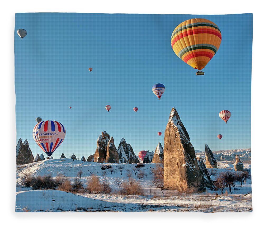 Wind Fleece Blanket featuring the photograph Hot Air Balloons Over Snow Covered Rock #3 by Izzet Keribar