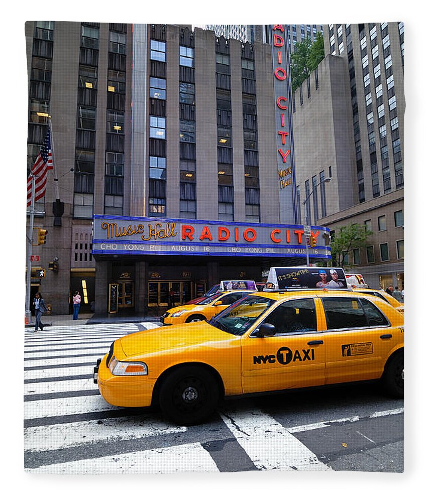Building Fleece Blanket featuring the photograph Yellow Cabs pass in front of Radio City Music Hall by Amy Cicconi