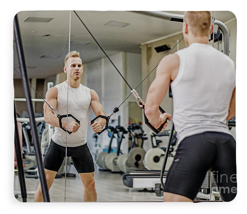 Handsome blond young man exercising pecs on gym equipment Fleece