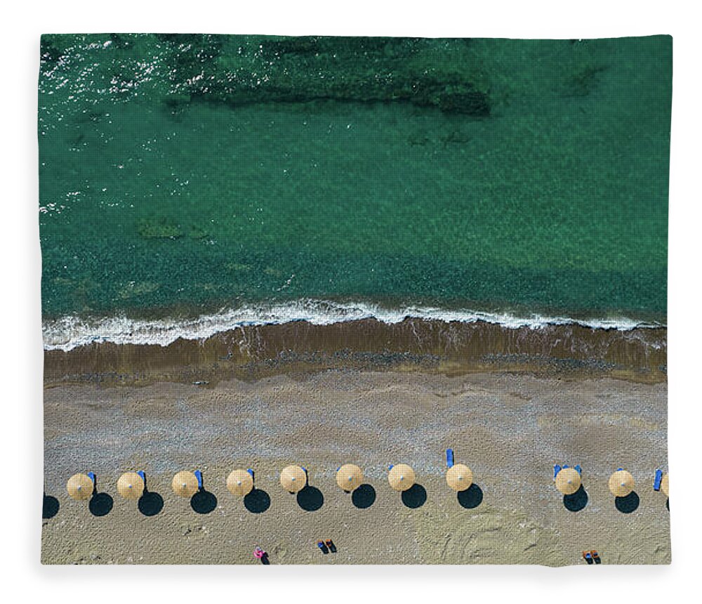 Summertime Fleece Blanket featuring the photograph Aerial view from a flying drone of beach umbrellas in a row on an empty beach with braking waves. by Michalakis Ppalis