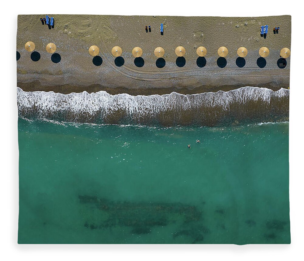  Beach Fleece Blanket featuring the photograph Aerial view from a flying drone of beach umbrellas in a row on a by Michalakis Ppalis