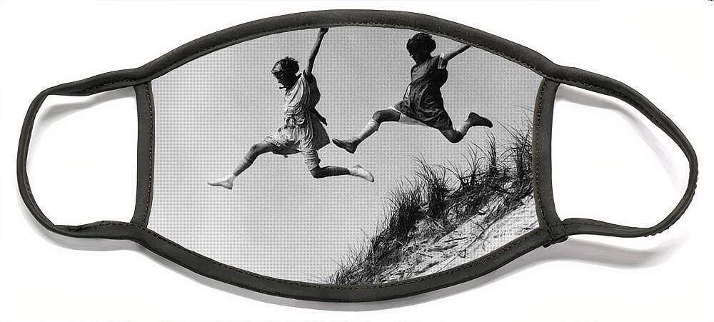 1920s Face Mask featuring the photograph Two Girls Leaping Off Sand Dune by H Armstrong Roberts and ClassicStock