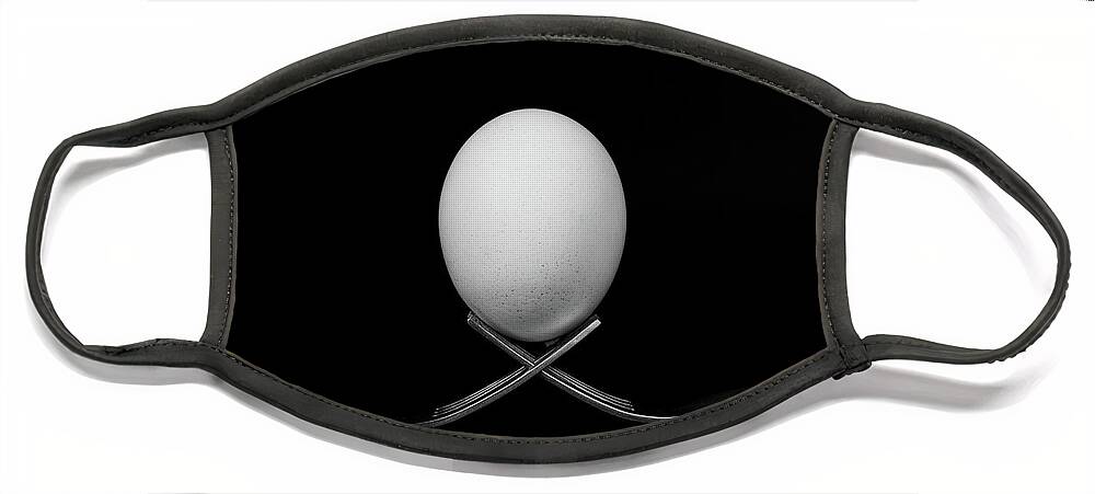 Egg Face Mask featuring the photograph White egg resting on two metal and shiny forks on a black backg by Michalakis Ppalis