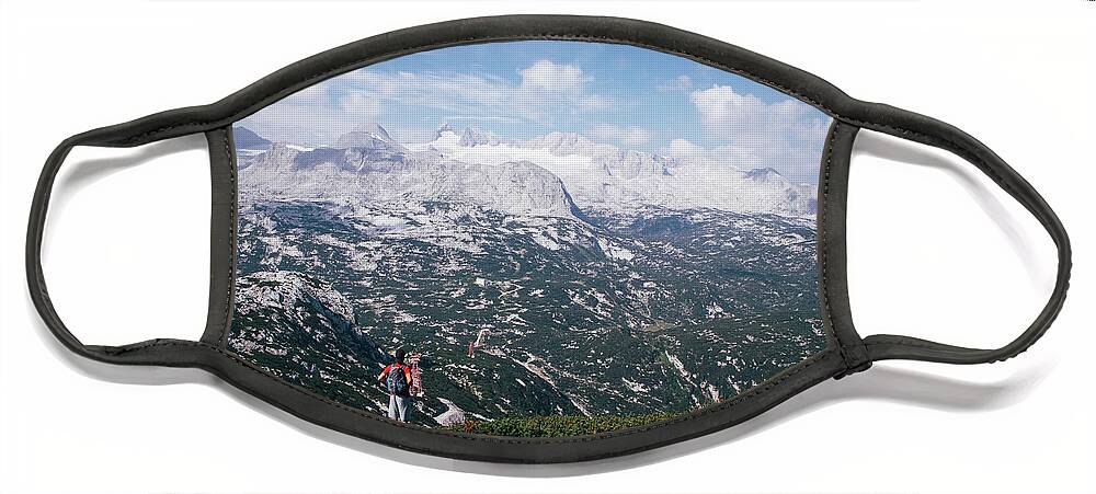 Sportive Face Mask featuring the photograph Man with a backpack looks at the Dachstein massif by Vaclav Sonnek