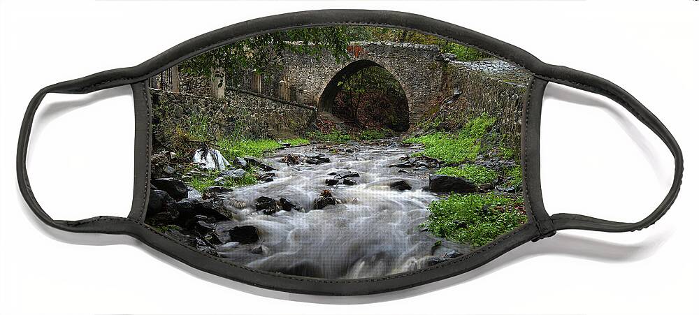 River Face Mask featuring the photograph Medieval stoned bridge water flowing in the river. by Michalakis Ppalis