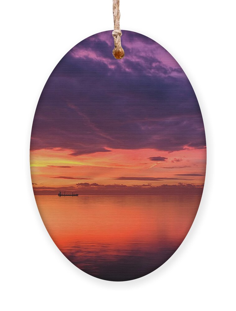 Sea Ornament featuring the photograph Cargo Ship Silhouette in a Dramatic and Colorful Sunset by Alexios Ntounas