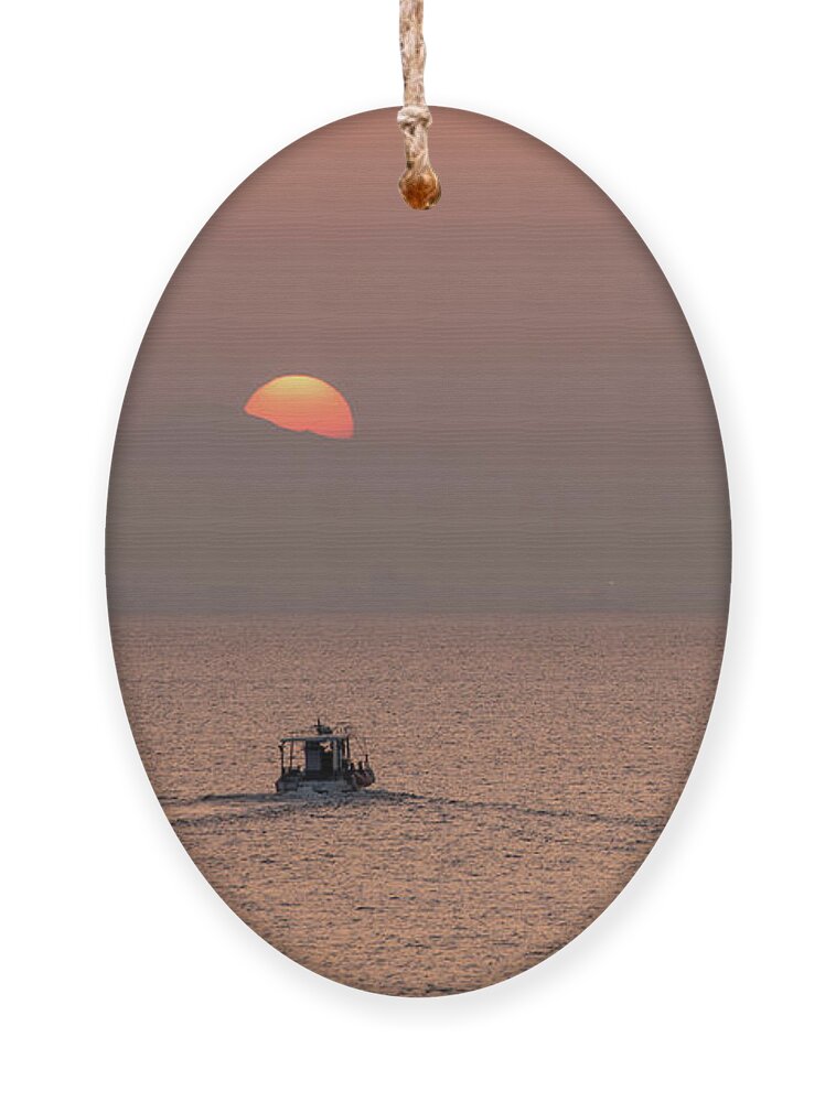 Sunset Ornament featuring the photograph Fishing boat sailing in the sea to catch fish at sunset by Michalakis Ppalis