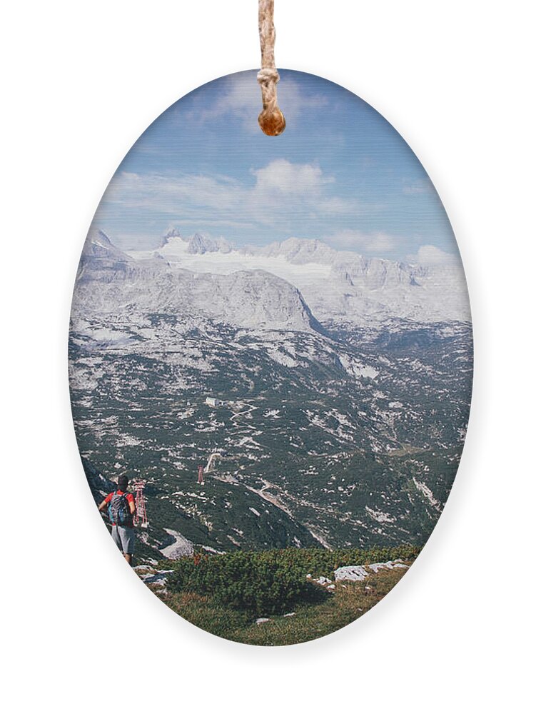 Sportive Ornament featuring the photograph Man with a backpack looks at the Dachstein massif by Vaclav Sonnek