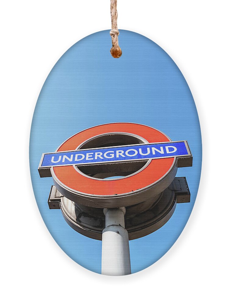 Underground Ornament featuring the photograph The iconic London Underground roundal sign against a blue sky ba by Jane Rix