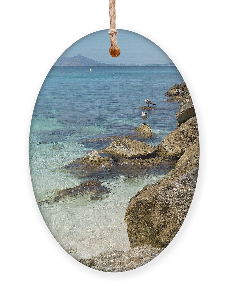 Mediterranean Ornament featuring the photograph Turquoise blue sea water and rocks in Calpe 2 by Adriana Mueller