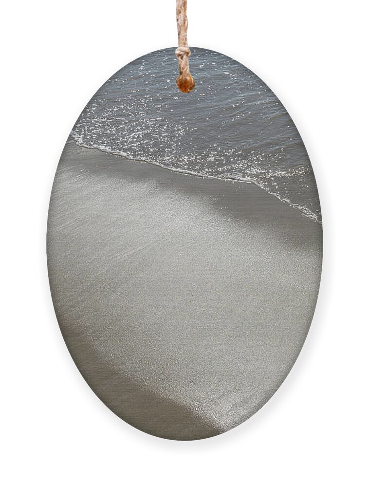 Sandy Beach Ornament featuring the photograph Wet sand, sea water and reflections of sunlight 2 by Adriana Mueller