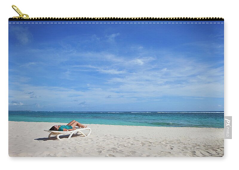 Tranquility Zip Pouch featuring the photograph A Woman Lays On A Lounge Chair On The by Leah Hammond / Design Pics