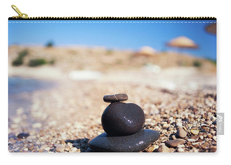 Water's Edge Zip Pouch featuring the photograph Balanced Stones On The Beach by Gm Stock Films