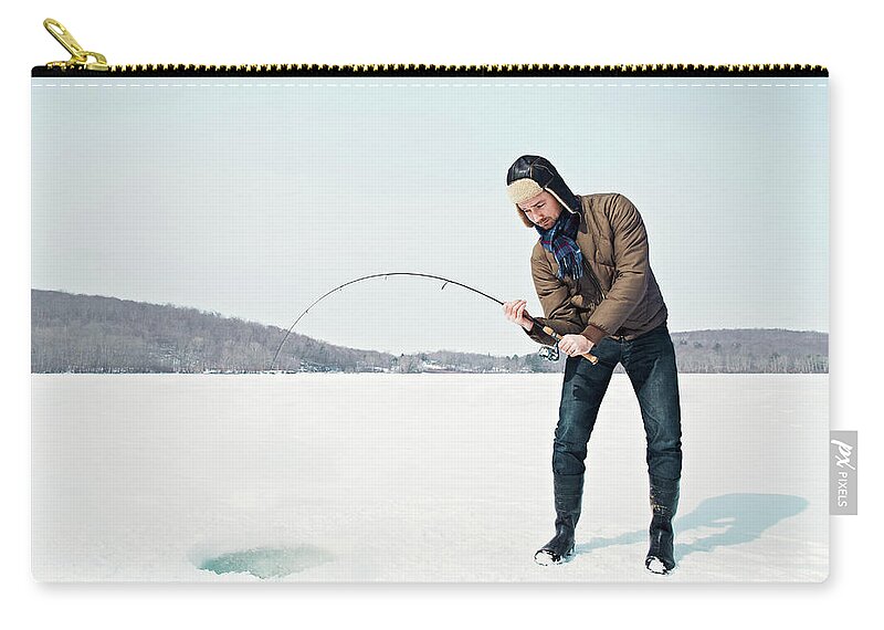 People Zip Pouch featuring the photograph Man Ice Fishing On Frozen Lake by Andy Ryan