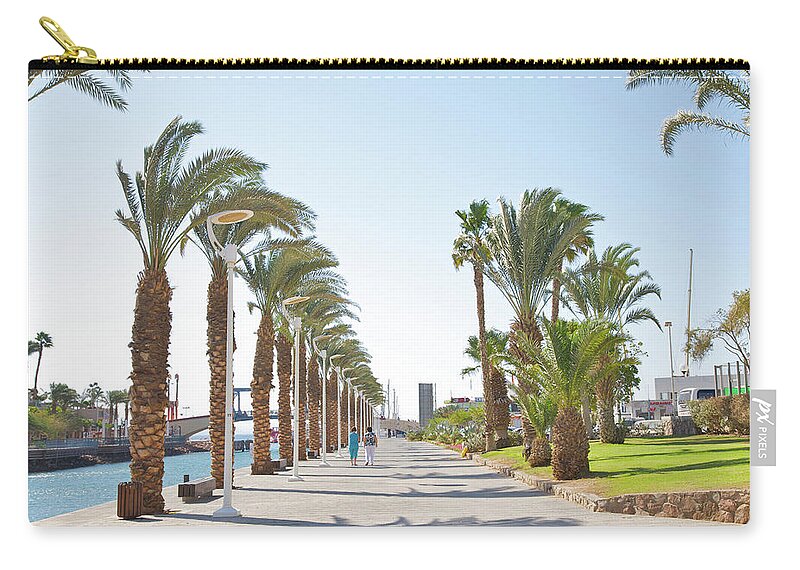 Tranquility Carry-all Pouch featuring the photograph People In Between Palms On Eilat Walkway by Barry Winiker