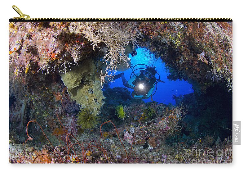 Arch Zip Pouch featuring the photograph A Diver Peers Through A Coral Encrusted by Steve Jones