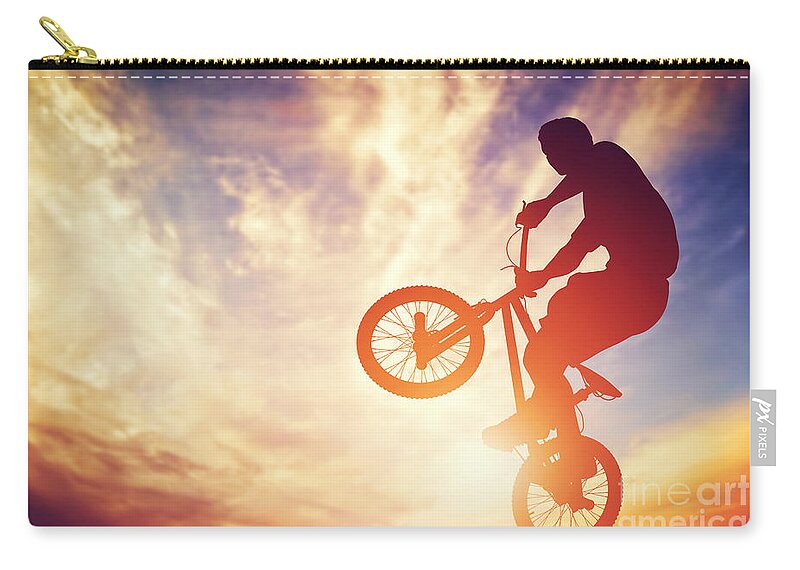Bike Zip Pouch featuring the photograph Man riding a bmx bike performing a trick against sunset sky by Michal Bednarek