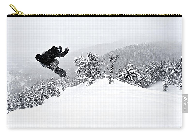 Recreational Pursuit Zip Pouch featuring the photograph A Man On A Snowboard Flies Through The by Derek Diluzio
