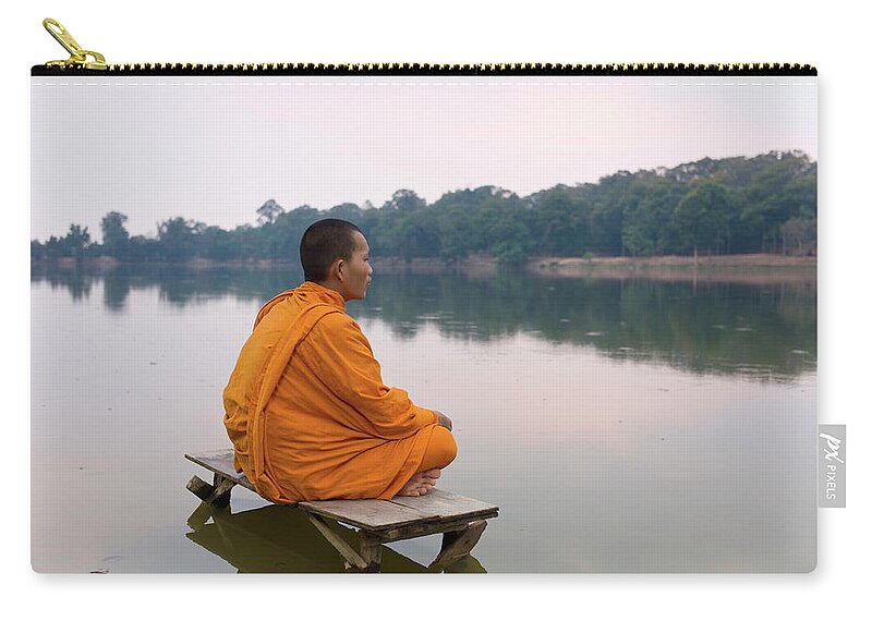 Three Quarter Length Zip Pouch featuring the photograph Buddhist Monk Sitting On Waters Edge by Martin Puddy