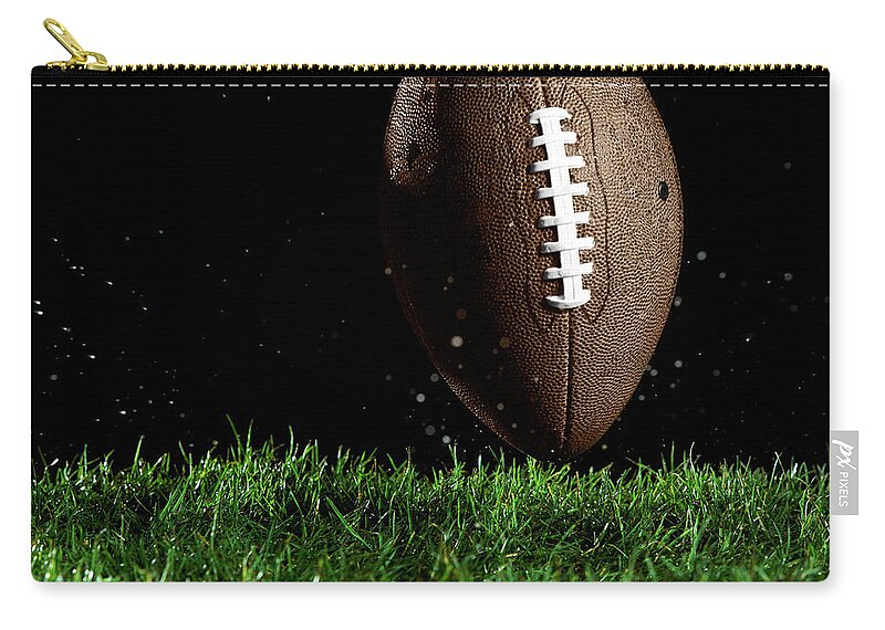 Grass Zip Pouch featuring the photograph Football In Motion Over Grass by Thomas Northcut
