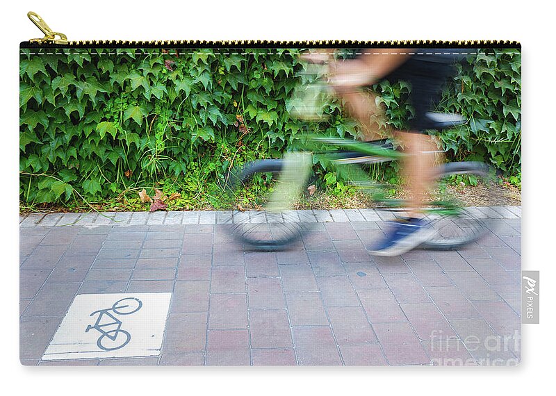Action Zip Pouch featuring the photograph Motion blurred cyclists to show speed, driving along a bike lane by Joaquin Corbalan