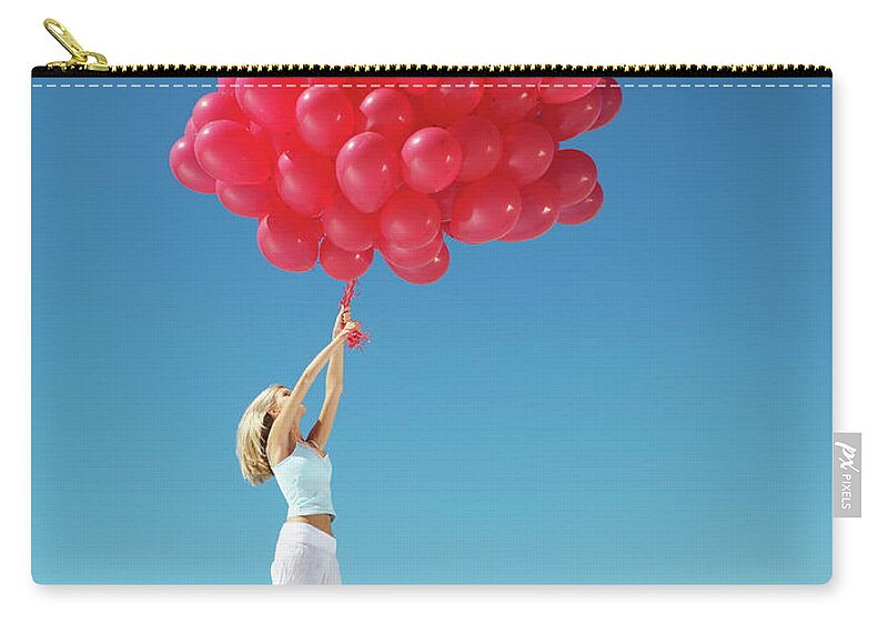 Hand Raised Zip Pouch featuring the photograph Young Woman Holding On To Large Bunch by Nick Dolding