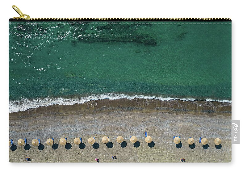 Summertime Carry-all Pouch featuring the photograph Aerial view from a flying drone of beach umbrellas in a row on an empty beach with braking waves. by Michalakis Ppalis