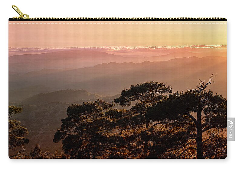 Dawn Zip Pouch featuring the photograph Silhouette of a forest pine tree during blue hour with bright sun at sunset. by Michalakis Ppalis